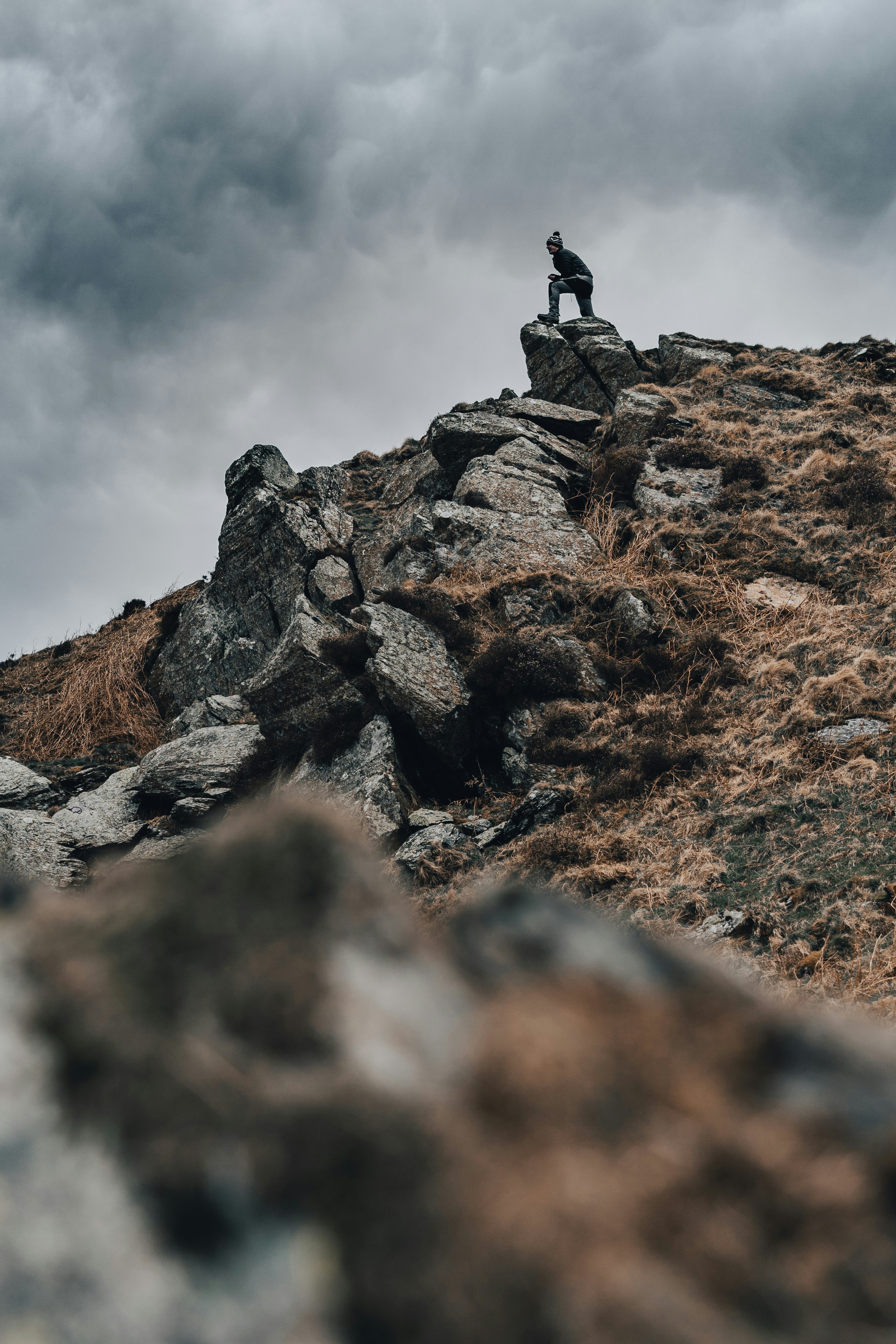 person standing on rock formation under cloudy sky during daytime